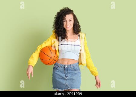 Ritratto di giovane donna elegante con palla per giocare a basket su sfondo a colori Foto Stock