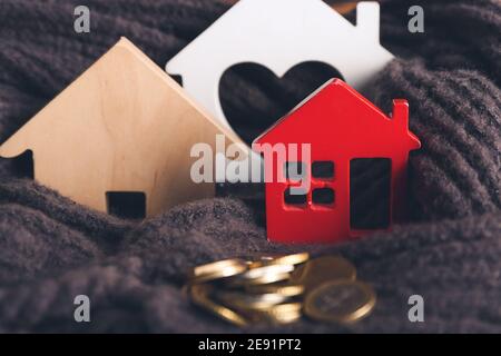 Figure di casa e monete su sciarpa calda, closeup. Concetto di stagione di riscaldamento Foto Stock