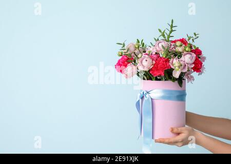 Mani con bellissimi fiori su sfondo colorato Foto Stock