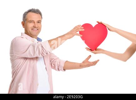 Donna che dà uomo maturo rosso cuore-forma scatola regalo su bianco sfondo Foto Stock