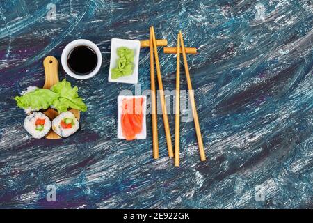 Involtini di sushi vegano con avocado, insalata di cetrioli e fondo nero di pomodoro. Concetto di cibo vegano sano. Foto Stock