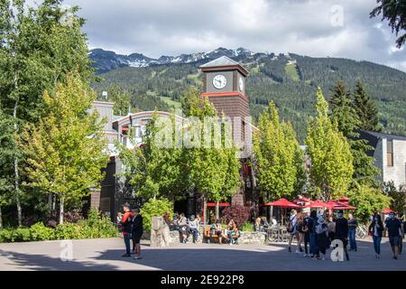 Whistler, Canada - Luglio 5,2020: Whistler Village pieno di persone in una giornata di sole con vista sulle montagne sullo sfondo. Messa a fuoco selettiva Foto Stock