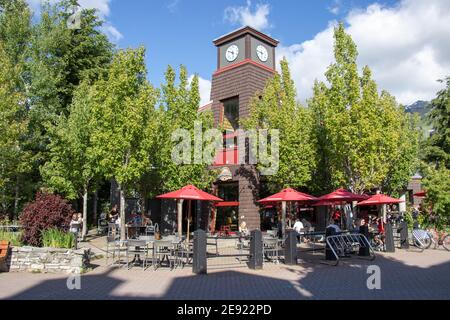 Whistler, Canada - Luglio 5,2020: Whistler Village pieno di persone in una giornata di sole con vista sulle montagne sullo sfondo. Messa a fuoco selettiva Foto Stock