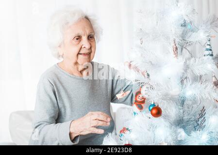 Sorridente donna anziana che decora l'albero di natale fantasia Foto Stock