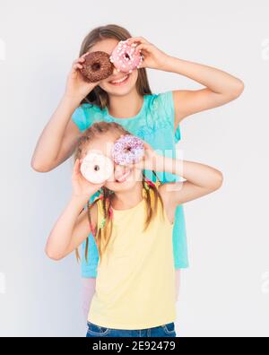 Due ragazze che fanno scherzi divertenti ed espressioni gioiose usando  fresco ciambelle al forno Foto stock - Alamy