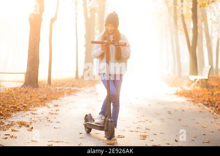 Ragazza adolescente carina su scooter nel parco autunnale Foto Stock