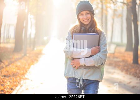 Bella ragazza con libri di testo nel parco autunnale Foto Stock