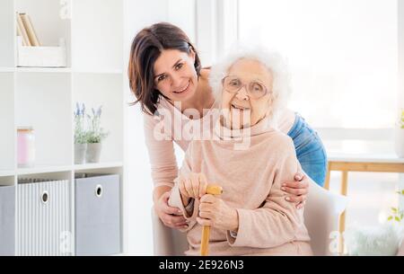 Donna anziana felice abbracciata da figlia a casa Foto Stock