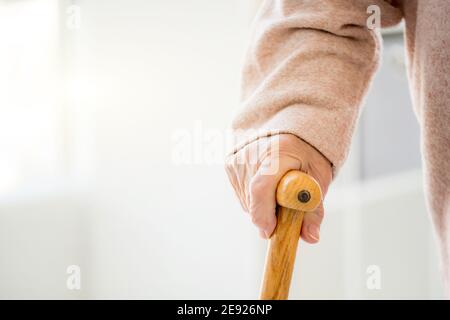 mano di donna anziana con canna su sfondo chiaro Foto Stock