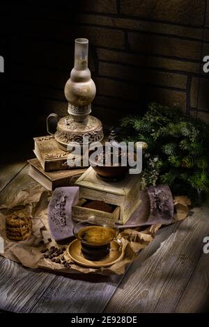 Vecchia lampada a olio fatta a mano, caffettiera e tazza di caffè su uno studio di legno sfondo Foto Stock