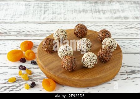 Tartufo di cioccolato vegano naturale fatto in casa con cacao e fiocchi di cocco su scrivania in legno su sfondo bianco. Foto Stock