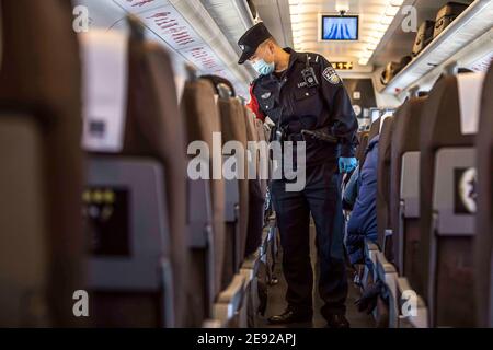 (210202) -- URUMQI, 2 febbraio 2021 (Xinhua) -- Zhang Jianzhi parla con i passeggeri mentre effettua il controllo di sicurezza sul treno D8806 nella regione autonoma Xinjiang Uygur della Cina nord-occidentale, 30 gennaio 2021. Zhang Jianzhi, un poliziotto ferroviario di 27 anni che lavora a Urumqi, si fa occupato del suo terzo lavoro di corsa del Festival di primavera. Lavorando per più di 40 giorni consecutivi durante la corsa di viaggio del Festival di Primavera dello scorso anno, Zhang si è sentito dispiaciuto per non essere stato con la sua fidanzata Zhao Lelin. Quest'anno, infine, ha proposto alla sua ragazza sul suo noto treno D8806. "Ho programmato questa proposta speciale sul treno per Foto Stock