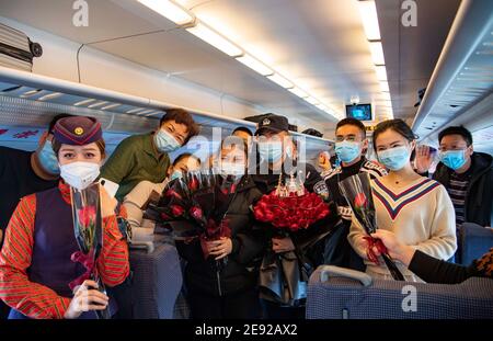 (210202) -- URUMQI, 2 febbraio 2021 (Xinhua) -- Zhang Jianzhi e Zhao Linle posano per foto con membri dell'equipaggio e passeggeri dopo una proposta di successo sul treno D8806 nella regione autonoma di Xinjiang Uygur, 30 gennaio 2021. Zhang Jianzhi, un poliziotto ferroviario di 27 anni che lavora a Urumqi, si fa occupato del suo terzo lavoro di corsa del Festival di primavera. Lavorando per più di 40 giorni consecutivi durante la corsa di viaggio del Festival di Primavera dello scorso anno, Zhang si è sentito dispiaciuto per non essere stato con la sua fidanzata Zhao Lelin. Quest'anno, infine, ha proposto alla sua ragazza sul suo noto treno D8806. "Ho pianificato Foto Stock