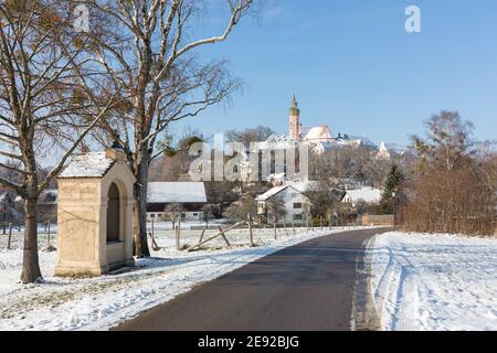 Vista lungo una strada verso l'abbazia di Andechs (Kloster Andechs). Con neve su entrambi i lati della strada. Foto Stock