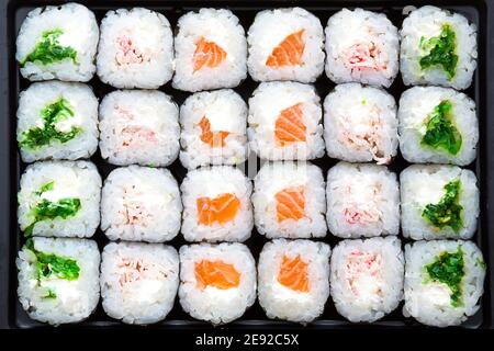 I rulli sono disposti in file, vista dall'alto, schema. Sfondo di sushi, cucina asiatica. Consegna Foto Stock