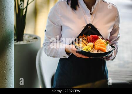 Diversi tipi di sashimi (ebi, sake, unagi, maguro) su ghiaccio in una ciotola in un ristorante Foto Stock