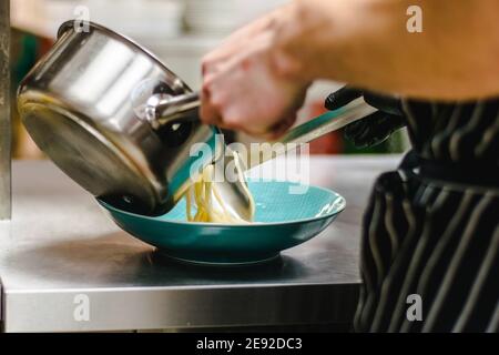 Chef che prepara zuppa di noodle ramen con carne, uova e verdure in un ristorante Foto Stock