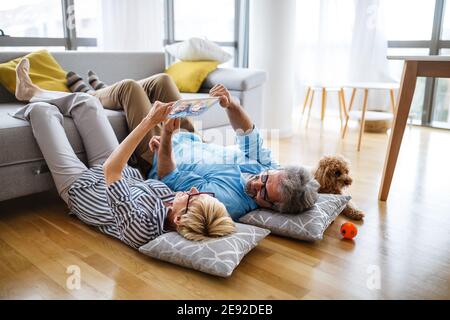 Felice coppia matura sorridente che usa il tablet digitale a casa Foto Stock