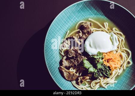 Zuppa di ramen di manzo con uova in camicia e verdure a un ristorante Foto Stock
