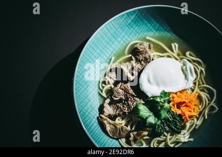 Zuppa di ramen di manzo con uova in camicia e verdure a un ristorante Foto Stock