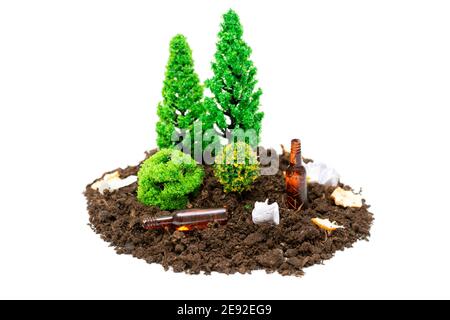 Set di foresta giocattolo in miniatura con un sacco di rifiuti, piccole bottiglie di vetro e carta che giace around.The concetto di mantenere foreste e parchi puliti. Foto Stock