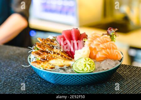 Diversi tipi di sashimi (ebi, sake, unagi, maguro) su ghiaccio in una ciotola in un ristorante Foto Stock