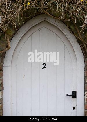 Cancello arcuato in legno in muratura di mattoni con mobili in ferro battuto nero. Westbury, Wiltshire, Inghilterra, Regno Unito. Foto Stock