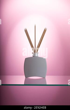 Deodorante aromatico reed sul tavolo in vetro nel bagno rosa. Foto Stock