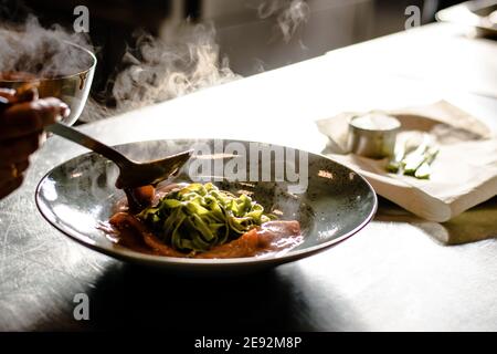 Bistecca di bue alla griglia e fiammato con tagliatelle di erbe verdi una purea di pomodoro in un ristorante Foto Stock