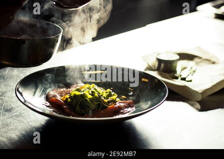 Bistecca di bue alla griglia e fiammato con tagliatelle di erbe verdi una purea di pomodoro in un ristorante Foto Stock