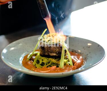 Bistecca di bue alla griglia e fiammato con tagliatelle di erbe verdi una purea di pomodoro in un ristorante Foto Stock