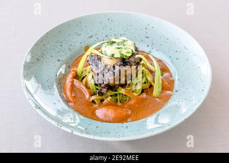 Bistecca di bue alla griglia e fiammato con tagliatelle di erbe verdi una purea di pomodoro in un ristorante Foto Stock