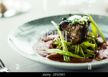 Bistecca di bue alla griglia e fiammato con tagliatelle di erbe verdi una purea di pomodoro in un ristorante Foto Stock