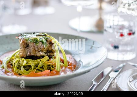 Bistecca di bue alla griglia e fiammato con tagliatelle di erbe verdi una purea di pomodoro in un ristorante Foto Stock