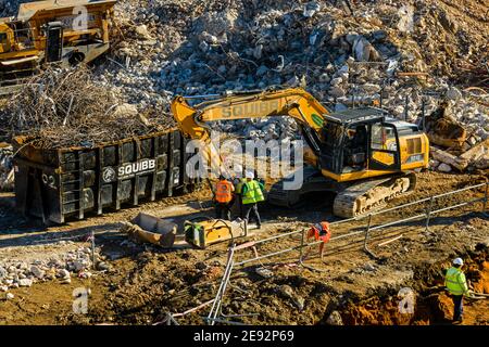 Sito di demolizione riciclaggio vista alta (cumulo di rifiuti di calcestruzzo, escavatore, frantumatore, rottami di metallo in skip, persone che lavorano) - Hudson House, York, Inghilterra, Regno Unito. Foto Stock