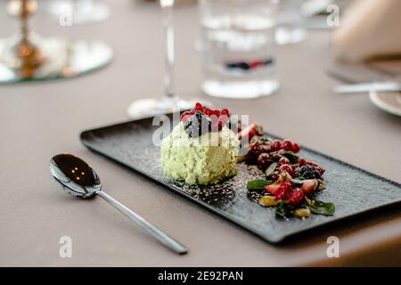 Gelato su un piatto nero con frutta e salsa in un ristorante Foto Stock