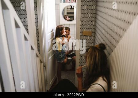 Madre con i bambini che spazzolano i denti in bagno Foto Stock