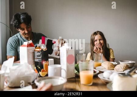 Sorridente padre e figlia che hanno la colazione insieme al tavolo da pranzo Foto Stock