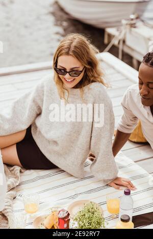 Vista ad alto angolo di una donna sorridente seduta da un amico durante picnic Foto Stock