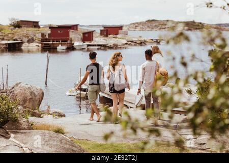 Vista posteriore degli amici che guardano il mare durante le vacanze estive Foto Stock
