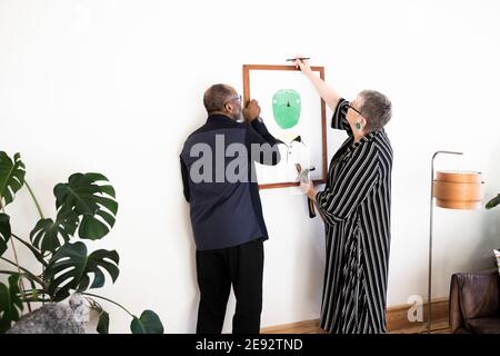 Coppia anziana appeso pittura sul muro a casa Foto Stock