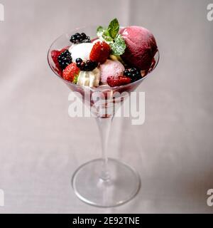 Gelato servito in una vetreria con diverse bacche Foto Stock