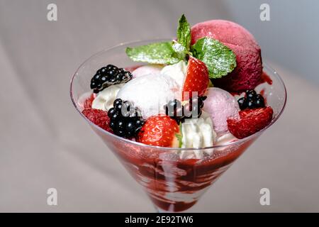 Gelato servito in una vetreria con diverse bacche Foto Stock