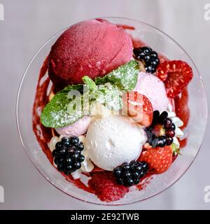 Gelato servito in una vetreria con diverse bacche Foto Stock