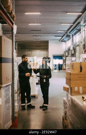 Colleghi di sesso maschile e femminile che discutono mentre si trovano in un magazzino logistico Foto Stock