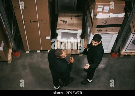 Uomo d'affari che discute con un collega maschile nel magazzino logistico Foto Stock