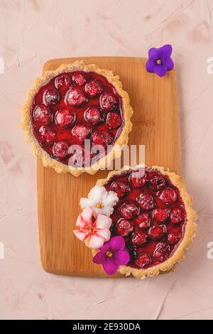 Mini torte primaverili fatte in casa con frutti di bosco decorati con fiori Foto Stock