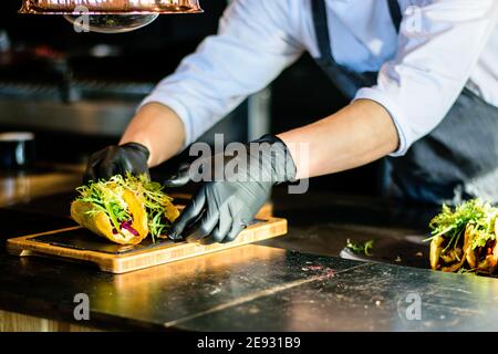 Uno chef che plating tacos in una cucina ristorante Foto Stock
