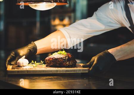 Chef che propone costolette grigliate su un bancone in un ristorante Foto Stock