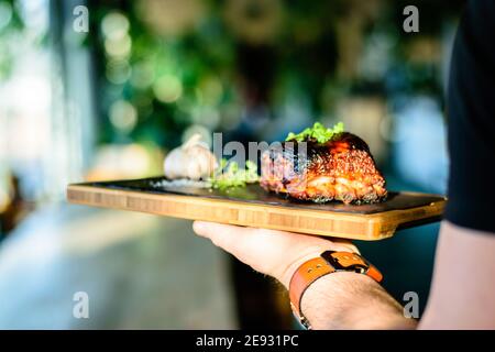 Chef che propone costolette grigliate su un bancone in un ristorante Foto Stock